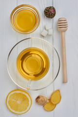 Cup of ginger tea with lemon and honey. Delicious beverage with honey, lemon and ginger in tea set on white background.