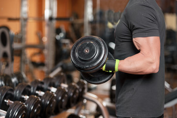 Fototapeta na wymiar Muscular man working out in gym doing exercises with dumbbells at biceps, strong male .