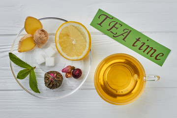 TEA time concept. Cup of herbal tea, dish with ginger, lemon and mint leaves on wooden background.