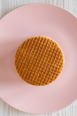 Stack of homemade Dutch stroopwafels with honey-caramel filling on a pink plate, top view.