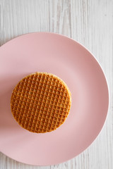 Stack of homemade Dutch stroopwafels with honey-caramel filling on a pink plate, view from above. Flat lay, overhead.