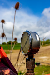 old rusty manometer on abandoned red agriculture machine in the field