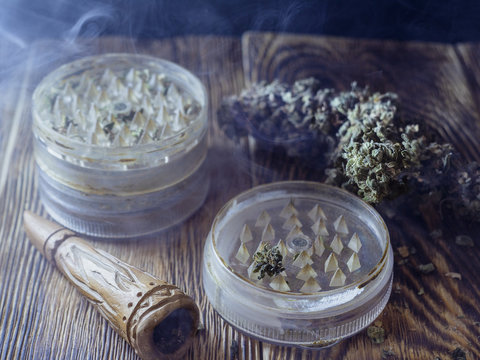 chillum grinder and marijuana lie in the smoke on a wooden table