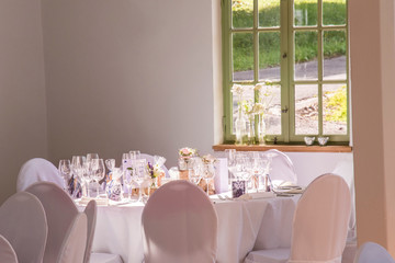 A room prepared for a wedding in a restaurant with tables beautifully laid in white
