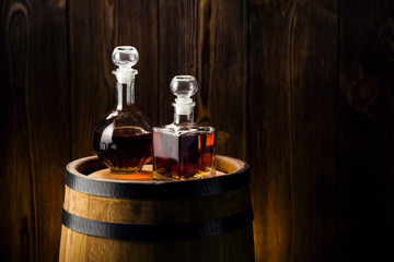 Fototapeta na wymiar brandy into glasses, strong drink in decanters on the barrel, oak barrel in the basement