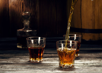 Cognac in glasses, in a wooden barrel cellar, strong refined alcoholic beverage