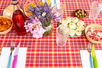 Above view of red checkered tablecloth with vegetable appetizers, fork and knifes.