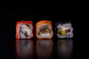 Japanese food,close-up  fresh sushi set of  three diferent types on black background with reflection