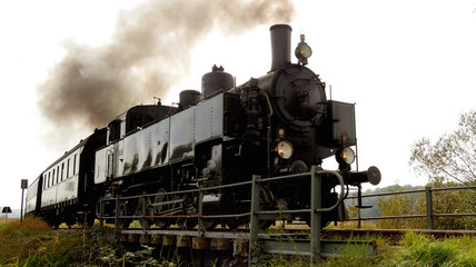 Fototapeta na wymiar Historical Retro Steam Engine Train Driving on Railroad Track