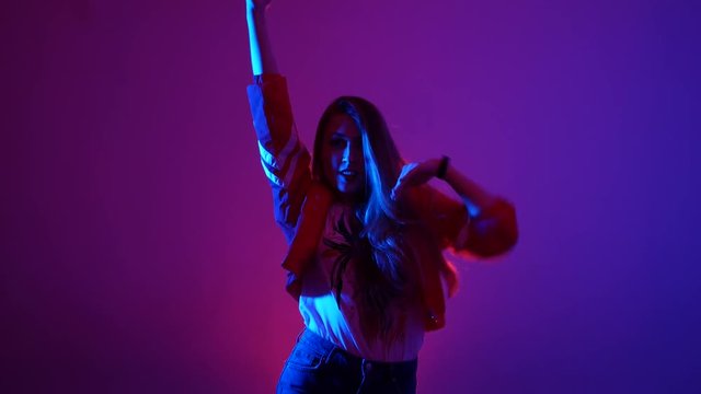 young beautiful woman dancing hip-hop, street dancing in the studio on a purple background, isolated