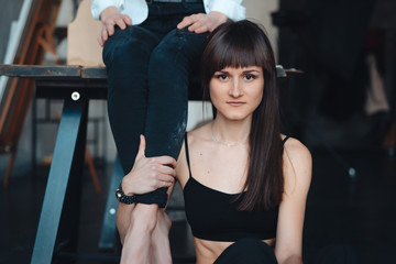 two girls are posing for the camera, one sitting on a table, other on the floor