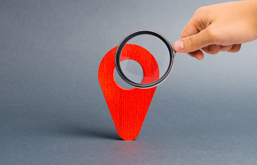 Magnifying glass is looking at red pointer location on a gray background. Concept of navigation and venue. Tourism and travel. Spying on the citizens.. Orientation around the city, location of events
