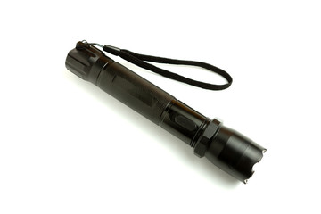A black metal flashlight with shocker at the white background. protection and security concept. for design and decoration.