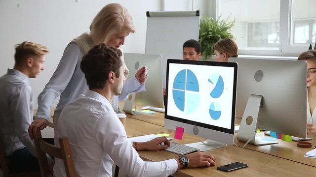 Diverse company employees working focus on senior mentor helping intern