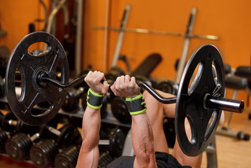 Handsome young muscular man close up, doing bench french press workout with barbell in gym .