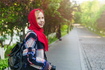 A middle aged woman with a red veil on her head in a park in summer.