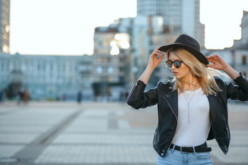 Outdoor fashion portrait of a pretty blonde woman wearing hat and mirror sunglasses. Space for text