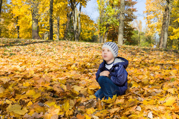 The boy sits thoughtfully on the ground
