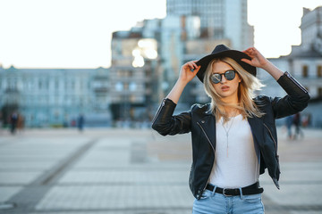 Outdoor fashion portrait of a beautiful blonde woman wearing hat and mirror sunglasses. Space for...