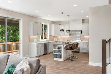 Kitchen in new elegant home with island, pendant lights, and stainless steel appliances