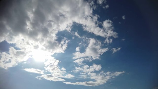 Timelapse blue summer sky with white fluffy clouds and beautiful plays of sunlight and right copy-space