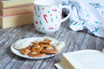 cup with tea, cakes and open book