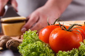 young woman slicing cheese in a gray apron