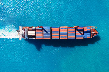 Cargo ship with containers against the blue sea, top view aerial. Logistics delivery concept