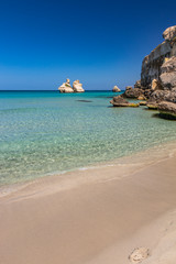 The bay of Torre dell'Orso, with its high cliffs, in Salento, Puglia, Italy. Turquoise sea and blue sky, sunny day in summer. A beach of fine white and pink sand. The stacks called the Two Sisters.