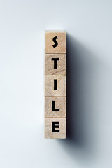 a line of wooden cubes with the word "style", on an uneven white background. Vertical frame
