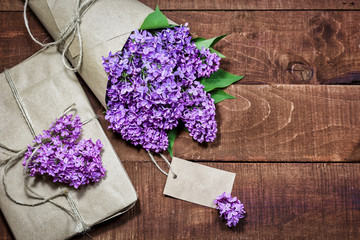 Gift and bouquet of lilacs on a wooden table