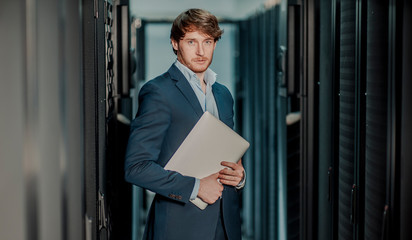   Young it engeneer business man with thin modern aluminium laptop in network server room