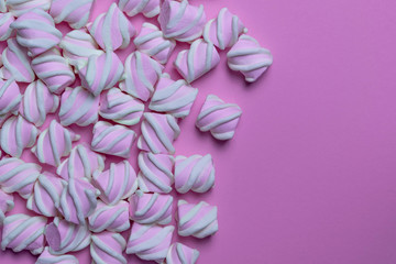 Many marshmallows are laid out on the left on a pink background. Free space for text, idea for design.