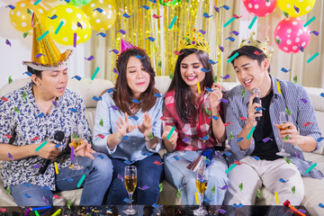 Cheerful young people singing at a birthday party