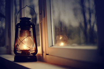 An old kerosene lamp stands on a white windowsill