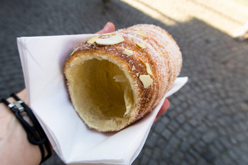 Trdelnik (spit cake) in Prague rolled grilled dough without filling but sugar crust and almonds in a girls hand
