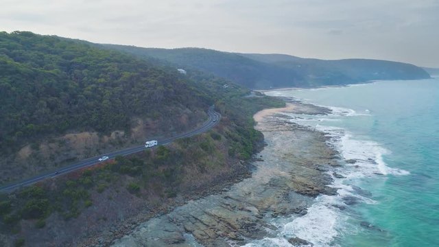 Slow rise over cars driving on the narrow winding and famous Great Ocean Road