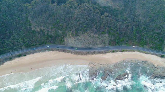 Tracking aerial shot of cars driving on the famous Great Ocean Road in Victoria, Australia