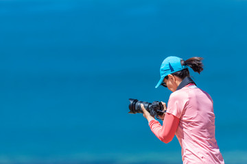 Landscape woman photographer taking photos in an amazing wilderness environment at Atacama Desert Andes mountains lagoons. A cut out silhouette over the blue waters with a mirror less camera shooting