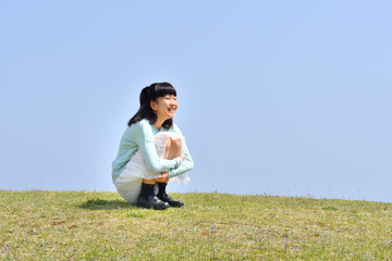 芝生広場に座る女の子（青空）