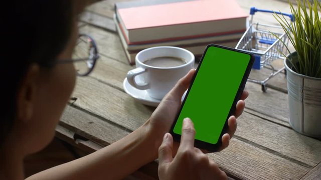 Over The Shoulder Shot Of Young Caucasian Female With Long Black Hair Using Mobile Phone With Chroma Key Green Screen. 