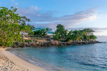 Beautiful white sand beach on upscale modern residential neighborhood property with colorful houses/ homes, on Caribbean island. Seaside/ ocean view luxury real estate.