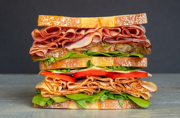 Fresh double layered sandwich with ham, lettuce, tomatoes, cheese on a toast bread, on black...