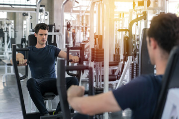 Handsome man lowering weight of fitness machine and working out in the fitness gym