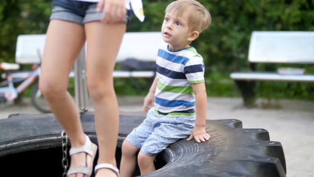 4k footage of little todler boy sitting on big tiry on children playground at park