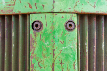 Front nose of farm equipment tractor. Metal background photo with rust, curvy metal vent and green chipping paint.
