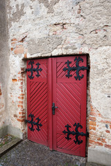 Red old gate with black fittings in an old wall