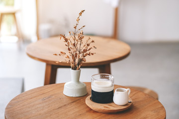 Closeup image of a glass of latte coffee on wooden table in minimal cafe
