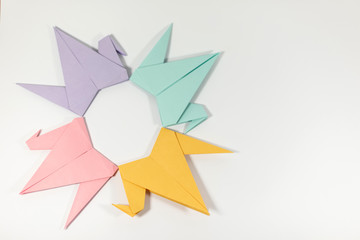 Origami paper cranes hand folded and arranged into a circular pattern, isolated on a white background