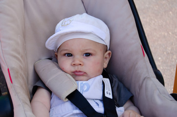 Cute six months old baby bou in the pushchair wih mosquito bites on his face